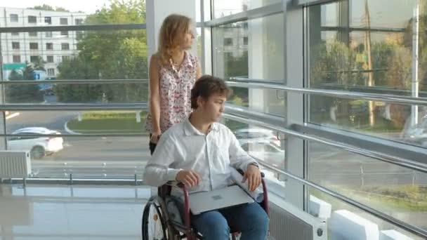 Ділова жінка крутить інвалідне крісло з інвалідним бізнесменом на інвалідному візку, який розмовляє по телефону — стокове відео