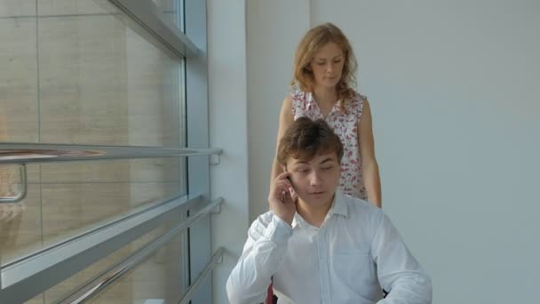 Business woman wheeling a wheelchair with a disabled businessman on a wheelchair who is talking on the phone — Stock Video