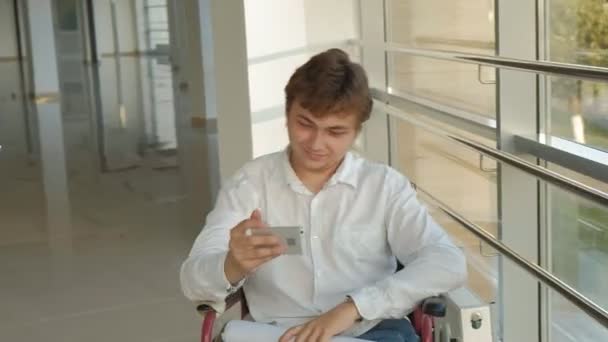 Επιχειρηματία με αναπηρία σε αναπηρικό καροτσάκι σε ένα παράθυρο χρησιμοποιεί smartphone — Αρχείο Βίντεο