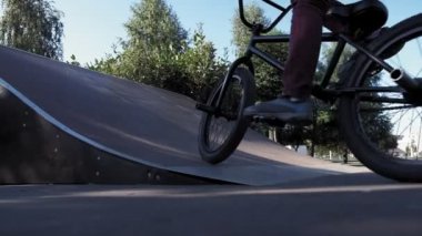 Bir çocuk Bmx Bisiklet hileler kaykay parkı güneşli bir günde biniyor. Çok yavaş hareket