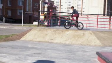 Bir çocuk Bmx Bisiklet hileler kaykay parkı güneşli bir günde biniyor. Çok yavaş hareket