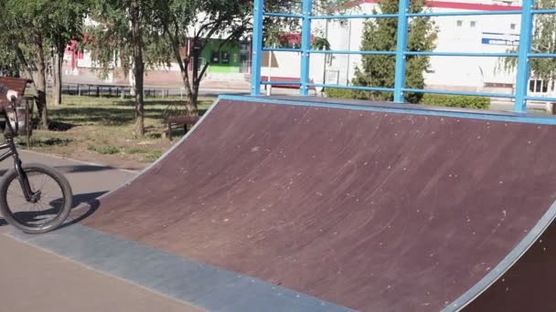 Um menino está montando BMX truques de ciclismo em um parque de skate em um dia ensolarado. Movimento super lento — Vídeo de Stock