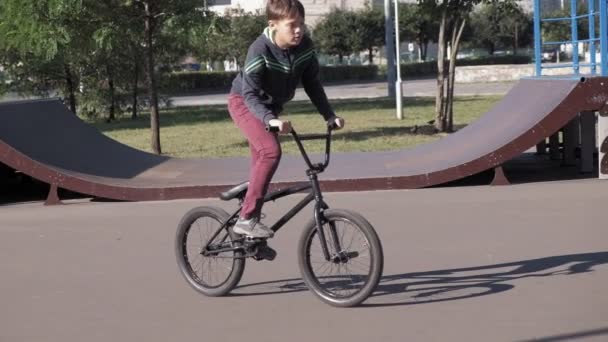 Хлопчик їхав Bmx їзда на велосипеді трюки на скейтборді парку на сонячний день. Супер-повільний рух — стокове відео