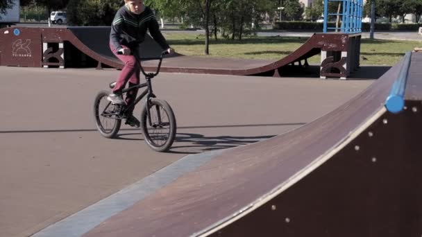 Un ragazzo sta cavalcando BMX ciclismo trucchi in un parco skateboard in una giornata di sole. Super rallentatore — Video Stock