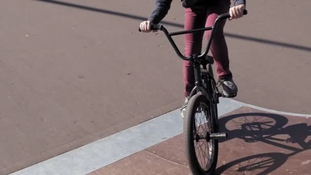 Um menino está montando BMX truques de ciclismo em um parque de skate em um dia ensolarado. Movimento super lento — Vídeo de Stock