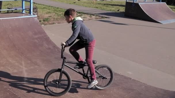 Chlapec na koni cyklo Bmx triky v parku skateboard za slunečného dne. Super pomalý pohyb — Stock video