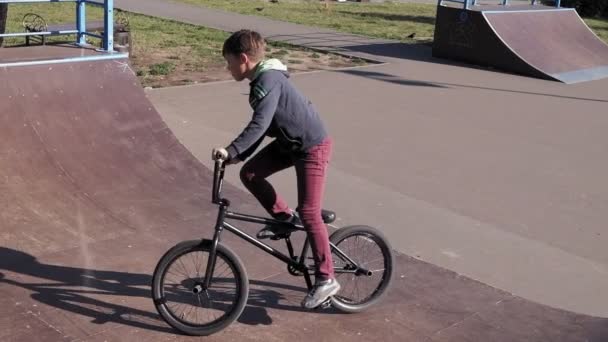 少年は、晴れた日に Bmx 自転車トリック スケート ボード公園を乗っています。超スローモーション — ストック動画