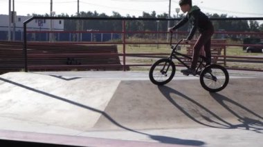 Bir çocuk Bmx Bisiklet hileler kaykay parkı güneşli bir günde biniyor. Çok yavaş hareket