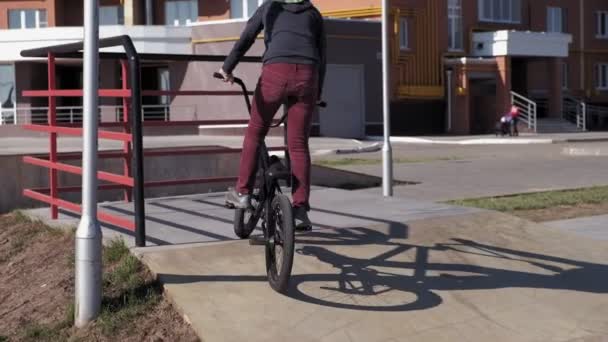 一个男孩在一个阳光明媚的日子 在滑板公园里骑着小轮自行车的把戏 超慢动作4K — 图库视频影像