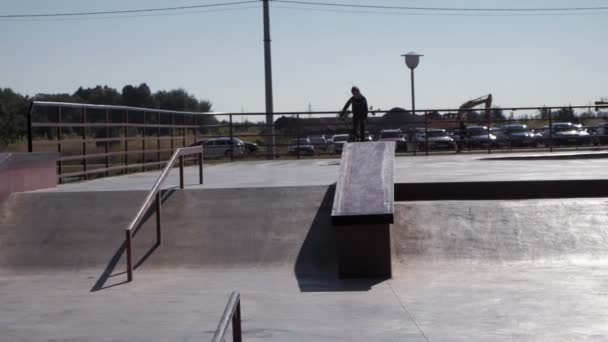 Un niño está montando trucos de ciclismo BMX en un parque de skate en un día soleado. Super cámara lenta — Vídeos de Stock