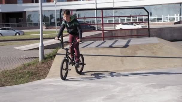 Хлопчик їхав Bmx їзда на велосипеді трюки на скейтборді парку на сонячний день. Супер-повільний рух — стокове відео