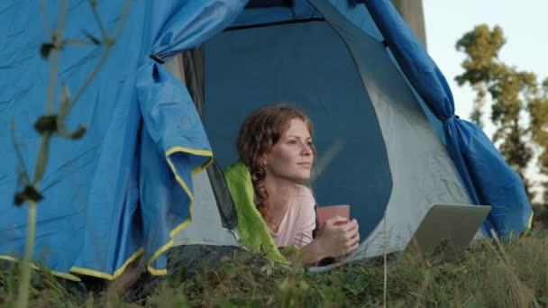 Young woman working behind a laptop in a tourist tent — Stock Video