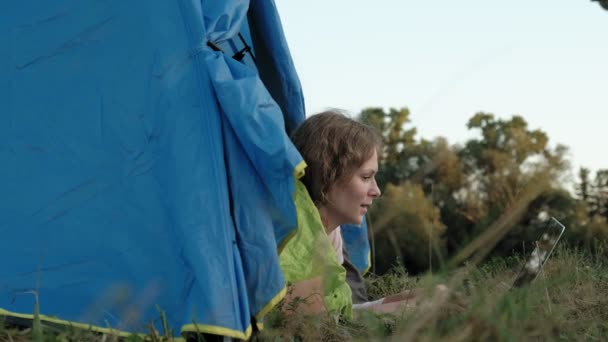 Jonge vrouw werken achter een laptop in een toeristische tent — Stockvideo