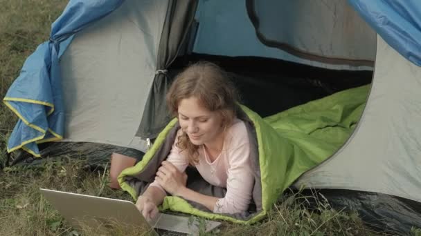 Young woman working behind a laptop in a tourist tent — Stock Video