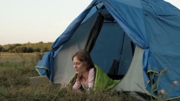 Bir dizüstü bilgisayar bir turist çadırda arkasında çalışan genç kadın — Stok video