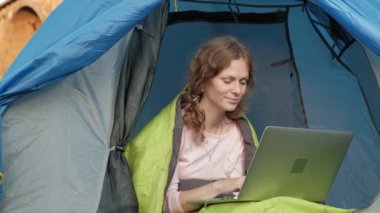 Bir dizüstü bilgisayar eski Köprüsü yakınlarında bir turist çadırda arkasında çalışan genç kadın