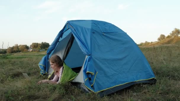 Jeune femme travaillant derrière un ordinateur portable dans une tente touristique — Video