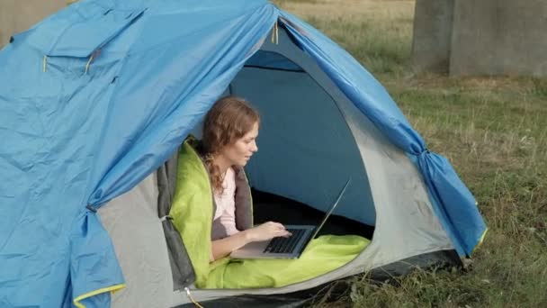 Jovem mulher trabalhando atrás de um laptop em uma tenda turística — Vídeo de Stock