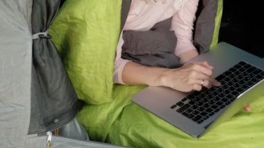 Bir dizüstü bilgisayar bir turist çadırda arkasında çalışan genç kadın