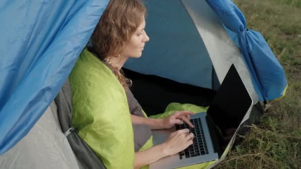 Young woman working behind a laptop in a tourist tent — Stock Video