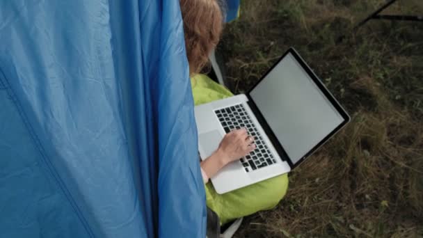 Молодая женщина, работающая за ноутбуком в туристической палатке — стоковое видео