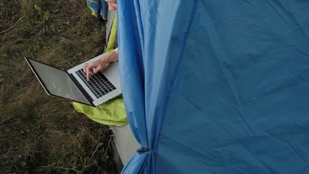 Ung kvinna som arbetar bakom en laptop i en turist-tält — Stockvideo