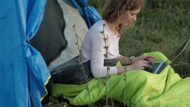 在一个旅游帐篷的笔记本电脑后面工作的年轻女子 — 图库视频影像