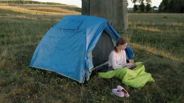 Jonge vrouw werken achter een laptop in een toeristische tent in de buurt van de oude brug — Stockvideo