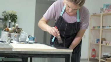 Atölye kadında ahşap kurullarında, antik bir efekt oluşturarak çalışıyor