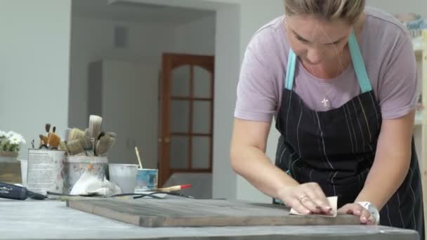 Die Frau in der Werkstatt arbeitet an Holzbrettern, die einen antiken Effekt erzeugen — Stockvideo