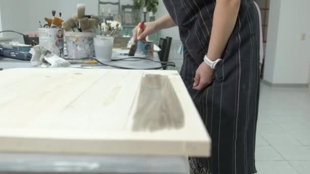 Die Frau in der Werkstatt arbeitet an Holzbrettern, die einen antiken Effekt erzeugen — Stockvideo