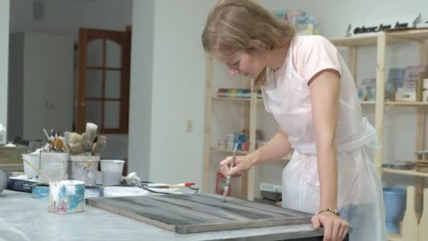 Жінка в майстерні працює над дерев'яними дошками, створюючи ефект старовини — стокове відео