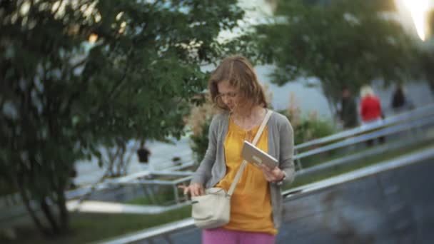 Hipster νεαρή γυναίκα μια βόλτα στο πάρκο πόλης επιχειρηματικό κέντρο — Αρχείο Βίντεο