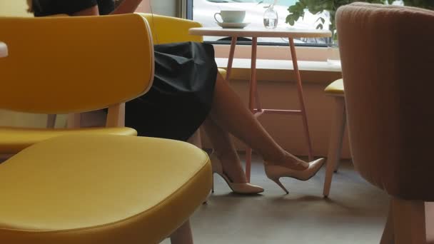 Деловая женщина сидит за столом в кафе, пьет кофе и работает на планшете — стоковое видео