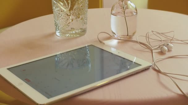 Ділова жінка сидить за столом у кафе п'є каву і працює на планшеті — стокове відео