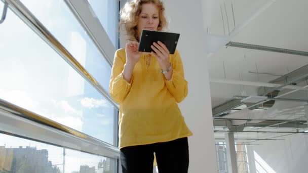 Joven mujer de negocios hermosa, junto a la ventana con una tableta — Vídeo de stock