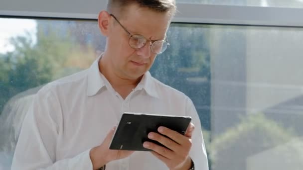 Reifer Geschäftsmann am Fenster mit Tablet — Stockvideo