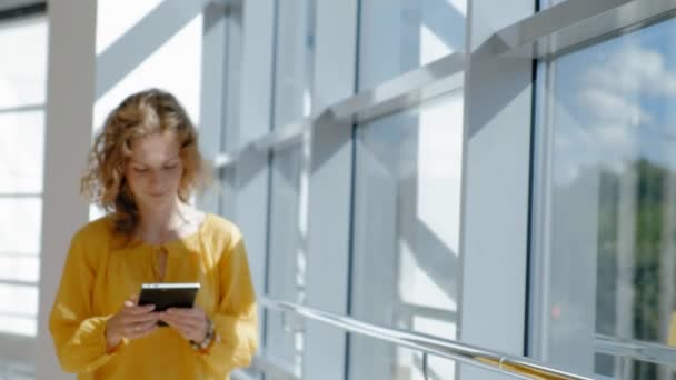 Jonge mooie zakenvrouw, bij het raam met een tablet — Stockvideo