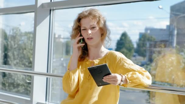 Joven mujer de negocios hermosa, junto a la ventana con una tableta — Vídeo de stock