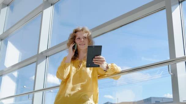 Joven mujer de negocios hermosa, junto a la ventana con una tableta — Vídeos de Stock