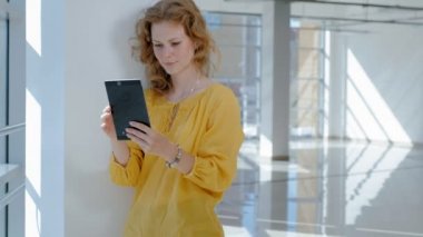 Pencerenin bir tablet ile genç güzel iş kadını