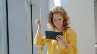 Pencerenin bir tablet 4k ile genç güzel iş kadını