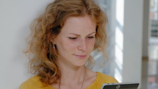 Young beautiful business woman, by the window with a tablet — Stock Video