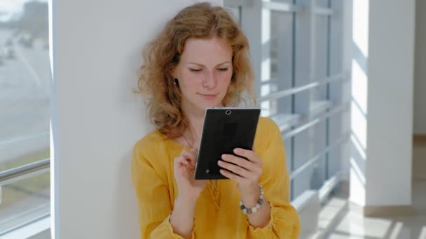 Giovane bella donna d'affari, dalla finestra con un tablet — Video Stock