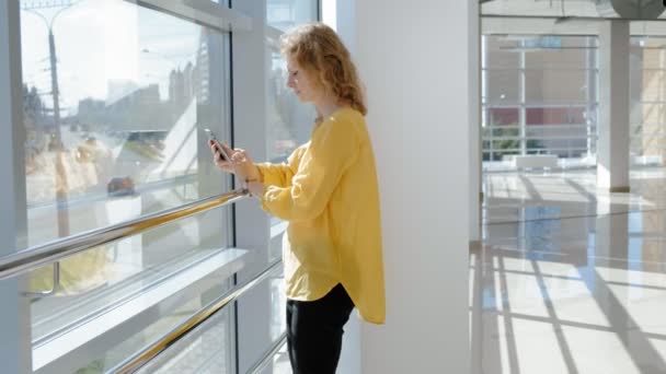 Joven mujer de negocios hermosa, junto a la ventana con una tableta — Vídeo de stock