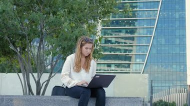 Şehir park iş merkezi içinde laptop üzerinde çalışan genç iş kadını
