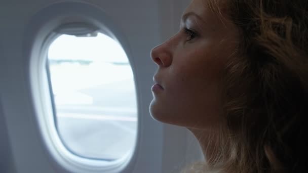 Zarif yetişkin kadın onun telefonunda Lombar açık mavi bir gökyüzü ve manifatura Mesajları bakarak bir uçak içinde oturuyor — Stok video