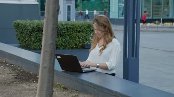 Jeune femme d'affaires travaillant sur ordinateur portable dans le centre d'affaires du parc de la ville — Video