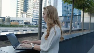 Şehir park iş merkezi içinde laptop üzerinde çalışan genç iş kadını