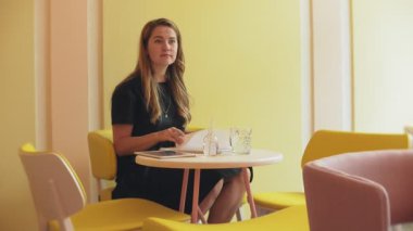 Bir kafede kahve içme ve bir tablet üzerinde çalışan bir masada oturan iş kadın